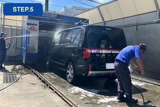 手洗い洗車でスタッフが洗い流しをしている写真